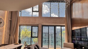 A modern living room with a curved sofa, a dining area, and a large TV screen. - Duplex Penthouse - River Bridge View in City Center, Thu Thiem, Ho Chi Minh City (Thành phố Hồ Chí Minh)