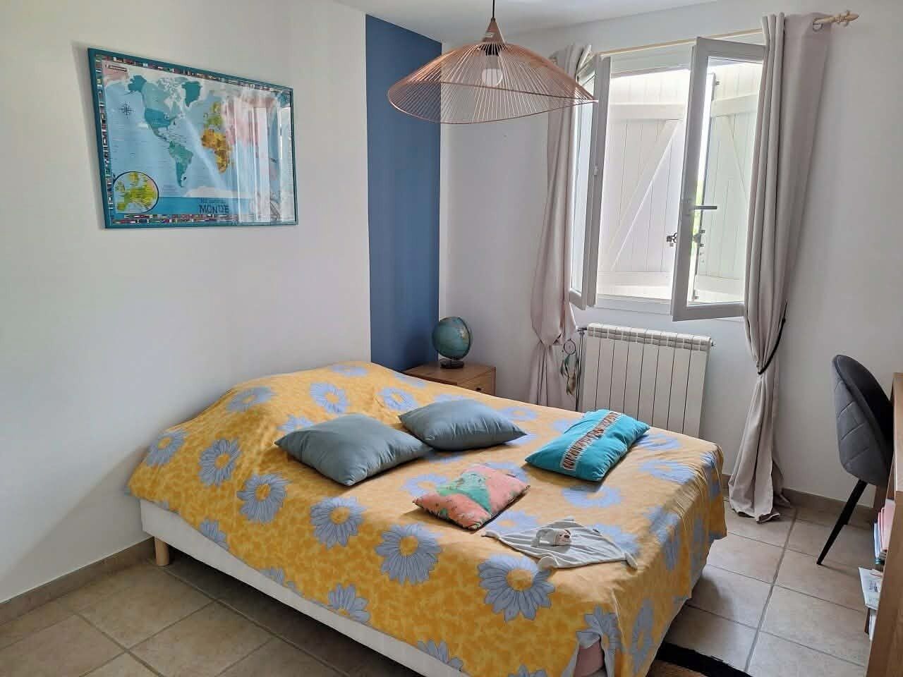 A bedroom with a bed, a globe, a map, and a window with curtains.