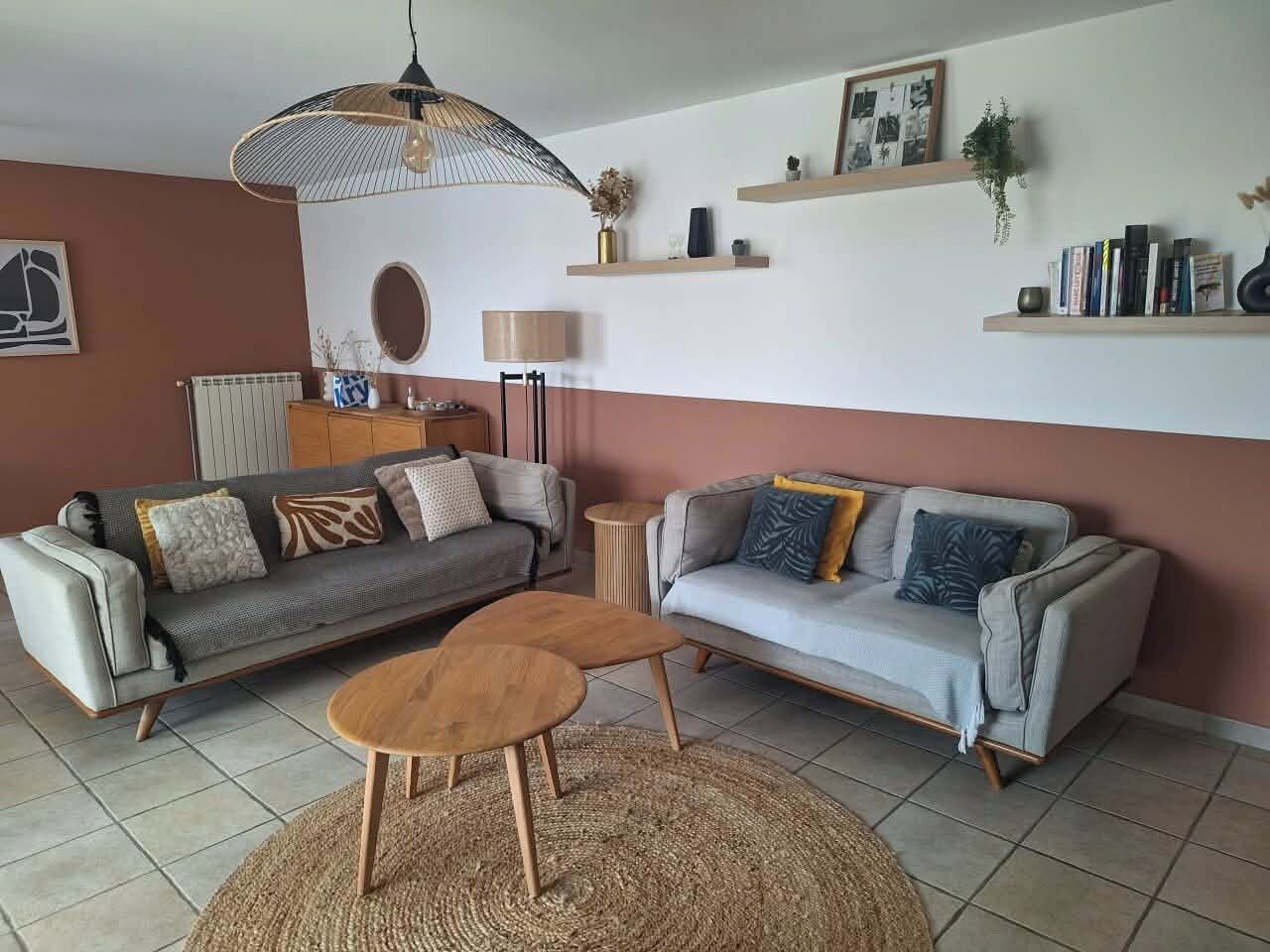 Un salon avec deux canapés, une table basse, une lampe et un luminaire suspendu.