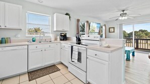A modern kitchen with white cabinets, a dishwasher, a stove, and a large window. - Beach Retreat 3BR/2BA – Across Paradise Park, Melbourne FL (Melbourne)