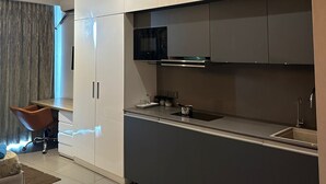 Une cuisine moderne avec des meubles blancs, un micro-ondes noir et un évier en acier inoxydable.