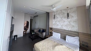 Une chambre d’hôtel moderne équipée d’un grand lit, d’un ventilateur de plafond, d’un bureau et d’un canapé.