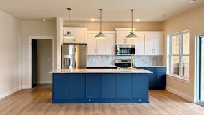 A modern kitchen with a central island, stainless steel appliances, and pendant lighting. - Lakes, Links, and Luxury at The Landing Overlook!  Private Balcony w/ Sunsets! (Branson)
