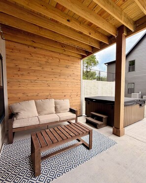 Une terrasse en bois avec un canapé et une table, un barbecue et une maison en arrière-plan.