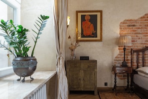 A room with a bed, a nightstand, a cabinet, a potted plant, a framed artwork, and a window with curtains. - Sienna, unique oasis with views in Old Towns heart (Kraków)