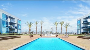 A modern hotel with a central pool, palm trees, and a clear sky. - The Sail & Sky Suite - Chic 2BR Elegance with Stunning Marina Panoramas (Marina del Rey)
