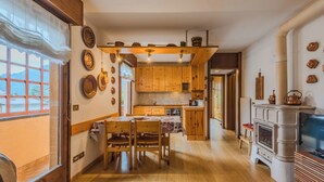 Een gezellige keuken met houten kastjes, een eettafel met stoelen, een open haard en een televisie.