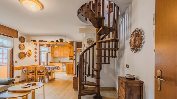 Een modern interieur met een spiltrap, houten meubels en een keukenhoek.