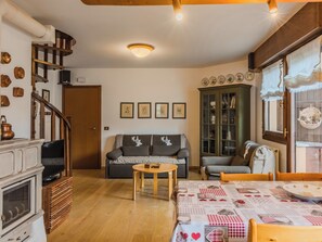 Un salon chaleureux avec une cheminée, un canapé, une table basse et un coin repas avec une table mise pour deux personnes.