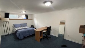 Un dormitorio con cama, escritorio, silla y ventana con cortinas.