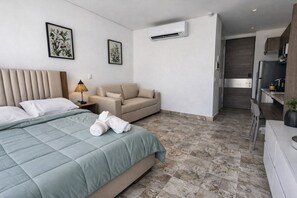 A hotel room with a bed, a sofa, a desk, and an air conditioning unit. - Newly Equipped Studio in Rodadero Sur - Beach, Restaurants and Tranquility (Gaira)