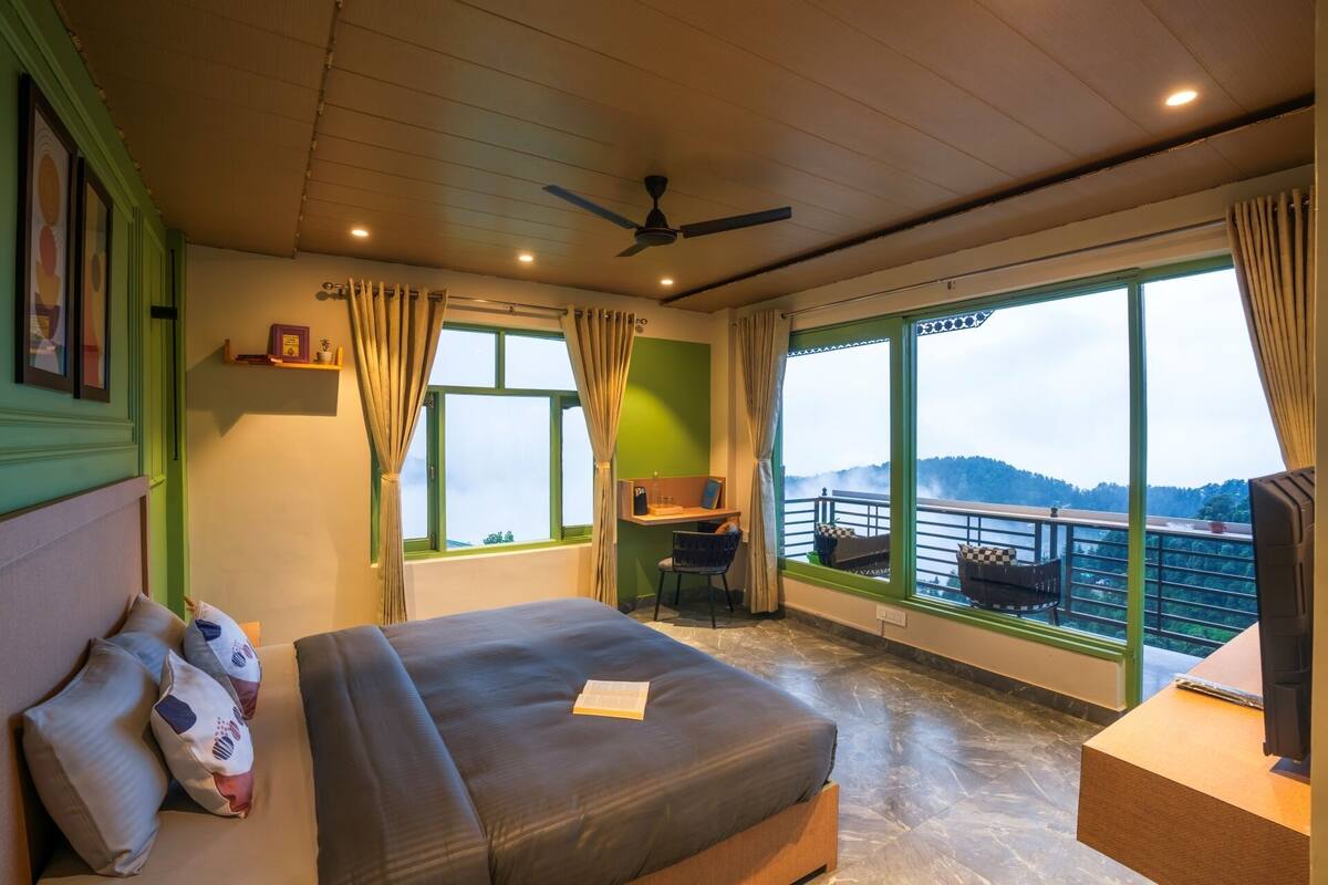 A bedroom with a bed, a desk, and a view of a balcony.