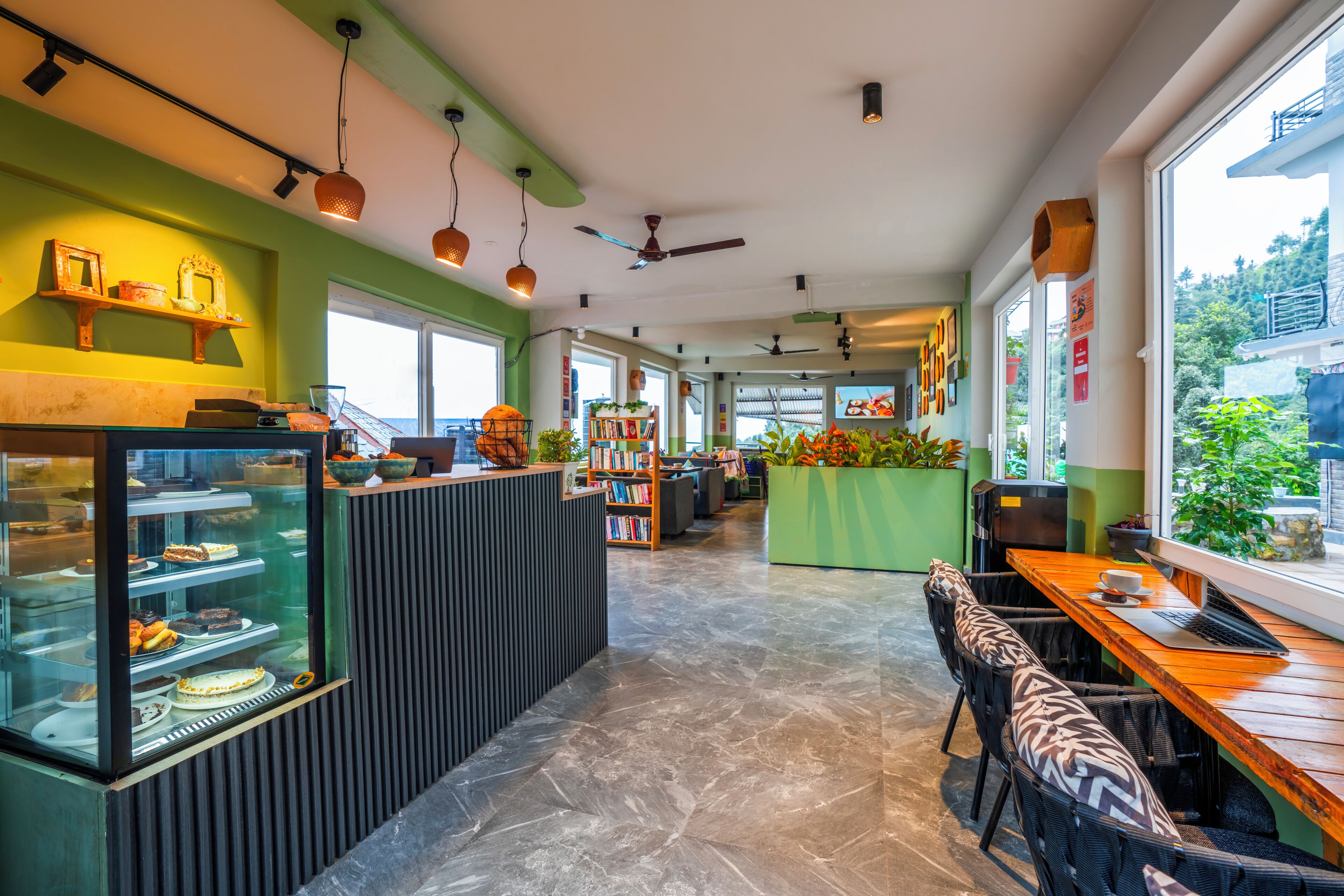 A restaurant with a glass display case, seating area, and a view of the outdoors.