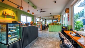 A restaurant with a glass display case, seating area, and a view of the outdoors.