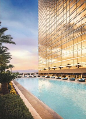 Un hotel moderno con una piscina grande, palmeras y vista al océano.