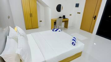 A hotel room with a bed, a desk, a wardrobe, and a door.