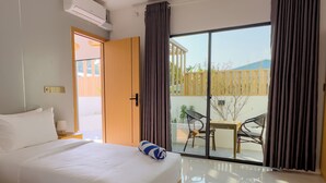 A hotel room with a bed, a window with curtains, a sliding glass door to an outdoor area, and a ceiling-mounted air conditioner. - Silver Bay Kamadhoo (Kamadhoo)