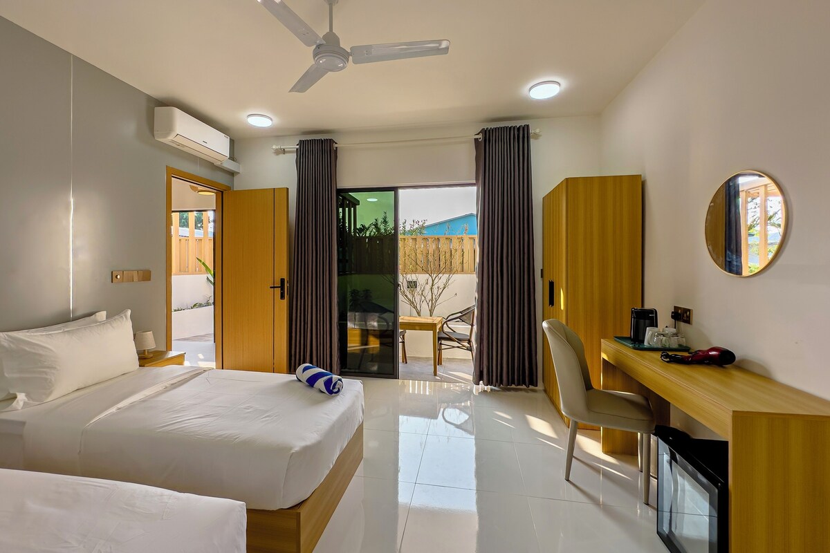A hotel room with a bed, desk, chair, and a ceiling fan.
