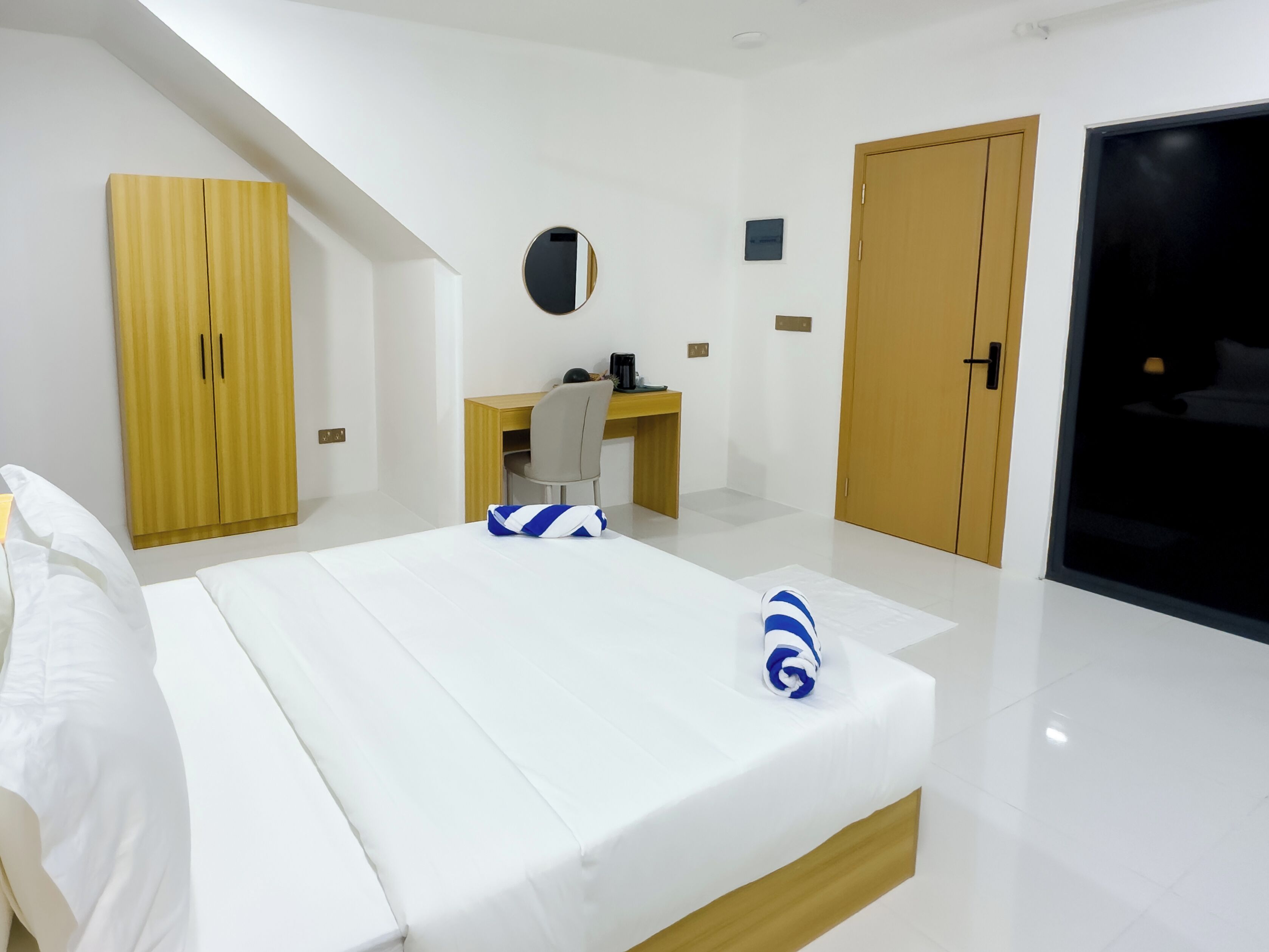 A hotel room with a bed, a desk, a wardrobe, and a door.