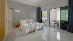 A modern hotel room with a bed, a ceiling fan, a sliding glass door to a balcony, and a wooden door. - Silver Bay Kamadhoo (Kamadhoo)