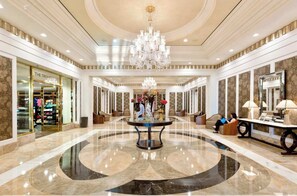 A spacious lobby with a central round table, a chandelier, and a store named "The Trumpet". - Stunning Trump Hotel Las Vegas Top Floor (Las Vegas)