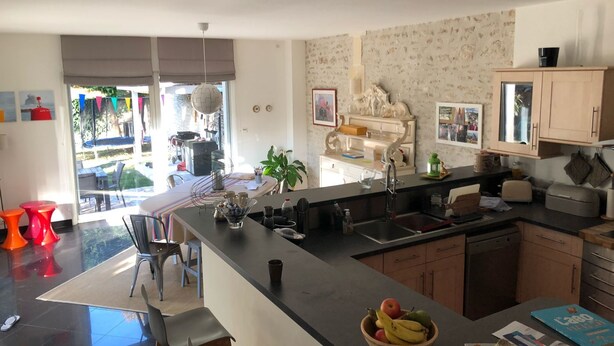 Una cocina moderna con una isla central, un comedor con sillas y vistas al exterior.