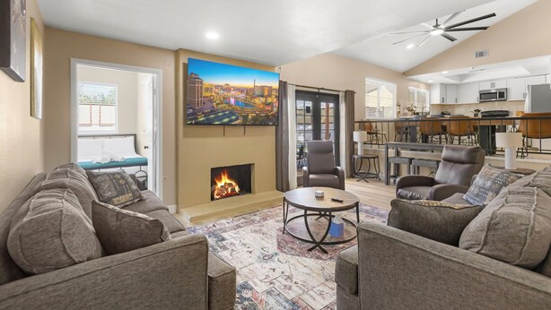 A living room with a fireplace, a dining area, and a kitchen. - Pool • Hot tub • Arcades • Air Hockey • Foosball • Mini-Golf • 20 Guests (Las Vegas)