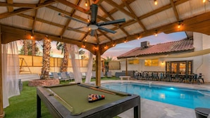A pool area with a pool table, lounge chairs, and a covered seating area. - Pool • Hot tub • Arcades • Air Hockey • Foosball • Mini-Golf • 20 Guests (Las Vegas)