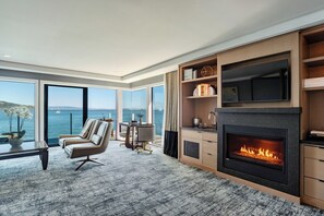 A modern living room with a fireplace, large windows, and a view of the sea. - The Inn Above Tide (Sausalito)