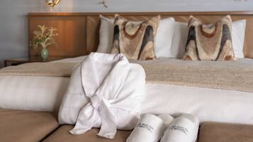 A neatly made bed with a white robe and slippers, a vase with flowers, and a bird on the wall.