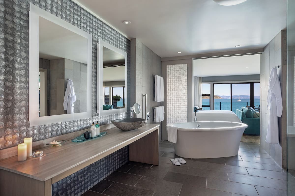 Un baño moderno con una bañera grande, un tocador con lavabo y un espejo amplio.