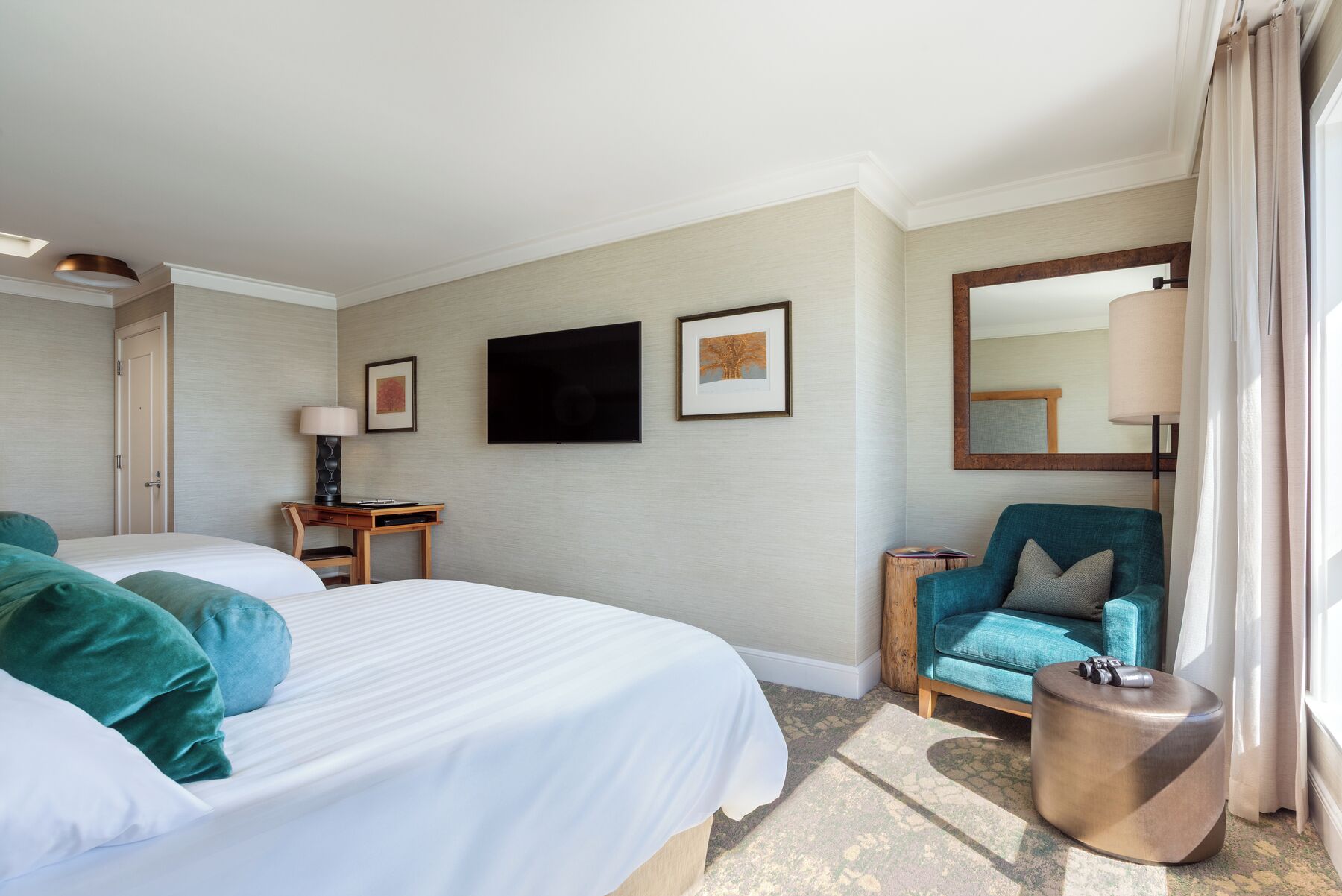 Une chambre d’hôtel avec deux lits, un bureau, une chaise, une télévision et un miroir.