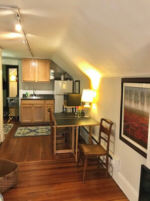 A cozy kitchen with wooden cabinets, a dining table with chairs, a lamp, and a framed picture on the wall. - Cleveland Clinic, 7 minutes from: Oak3 (Cleveland Heights)