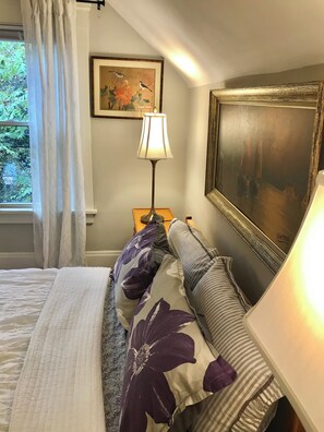 A bedroom with a bed, a nightstand, a lamp, a painting, and a window with curtains. - Cleveland Clinic, 7 minutes from: Oak3 (Cleveland Heights)