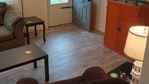 A living room with a sofa, a coffee table, a cabinet, a door, and a television.