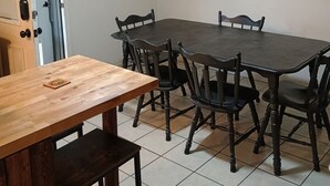 A dining area with a wooden table and chairs, a ceiling fan, a fire extinguisher, and a wall-mounted phone.