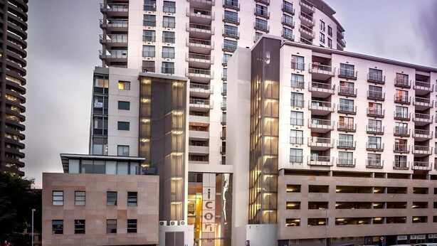 Ett hotell med flera våningar, balkonger, en parkeringsplats och en modern arkitektonisk design.