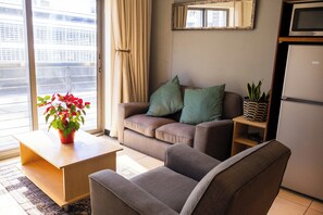 Ein Wohnzimmer mit Sofa, Sesseln, Couchtisch und einer Zimmerpflanze.