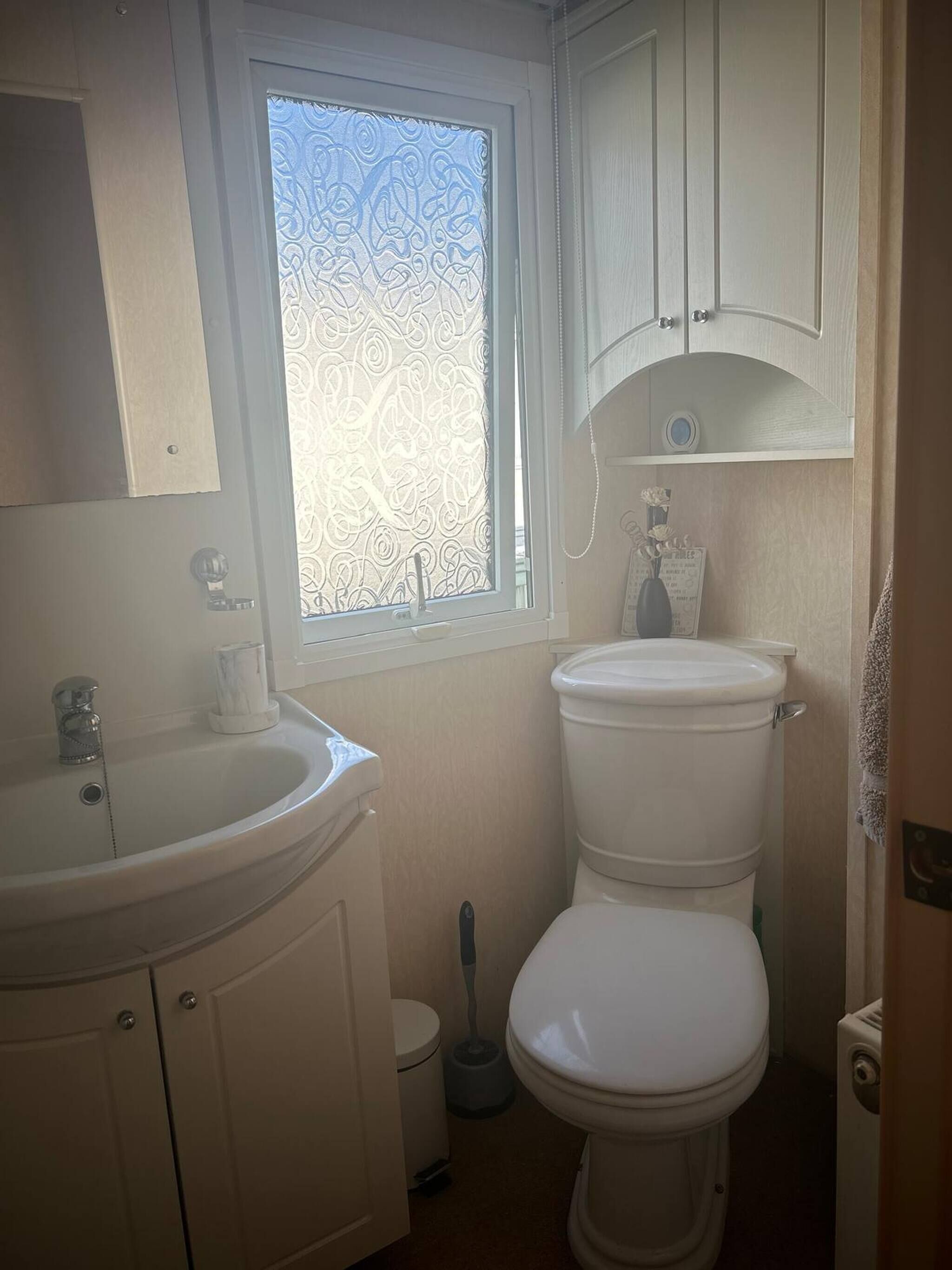 Et badeværelse med toilet, håndvask og vindue.