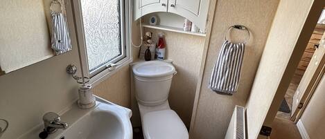 Een kleine badkamer met een wastafel, toilet en raam.