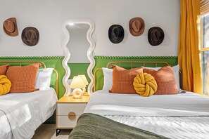 Habitación de hotel con dos camas, una mesita de noche, un espejo y una ventana con cortinas.