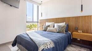Ein Schlafzimmer mit einem Bett, einem Fernseher, einem Holz-Kopfteil und Blick ins Freie.