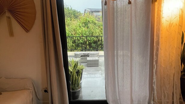 A room with a bed, a small table, a potted plant, and a view of greenery outside. - Cosy furnished studio, quiet, nature (Saint-Joseph)