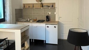 A compact kitchen with a white refrigerator, a sink, and a clock on the wall. - Cosy furnished studio, quiet, nature (Saint-Joseph)
