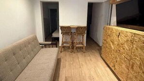 Ett modernt vardagsrum med en soffa, ett litet bord med två stolar och en vägg som har en träpanel som accent.