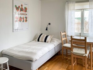 A bedroom with a single bed, a desk with a chair, a window with curtains, and a wall-mounted lamp. - 3 Person Holiday Home in Dalaro (Dalaro)