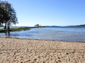 A sandy beach with a calm lake, trees, and a clear sky. - 3 Person Holiday Home in Dalaro (Dalaro)