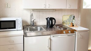 A compact kitchen with a white microwave, stainless steel sink, and a coffee maker. - 3 Person Holiday Home in Dalaro (Dalaro)