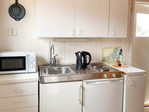 A compact kitchen with a white microwave, stainless steel sink, and a coffee maker. - 3 Person Holiday Home in Dalaro (Dalaro)
