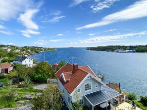 A coastal house with a red roof, a covered porch, and a view of the sea. - 3 Person Holiday Home in Dalaro (Dalaro)